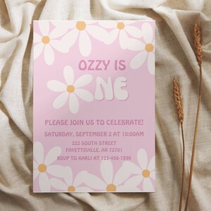 May include: Pink birthday party invitation with white daisies and the text "Ozzy is One" in a pink and white font. The invitation includes the date, time, address, and RSVP information.