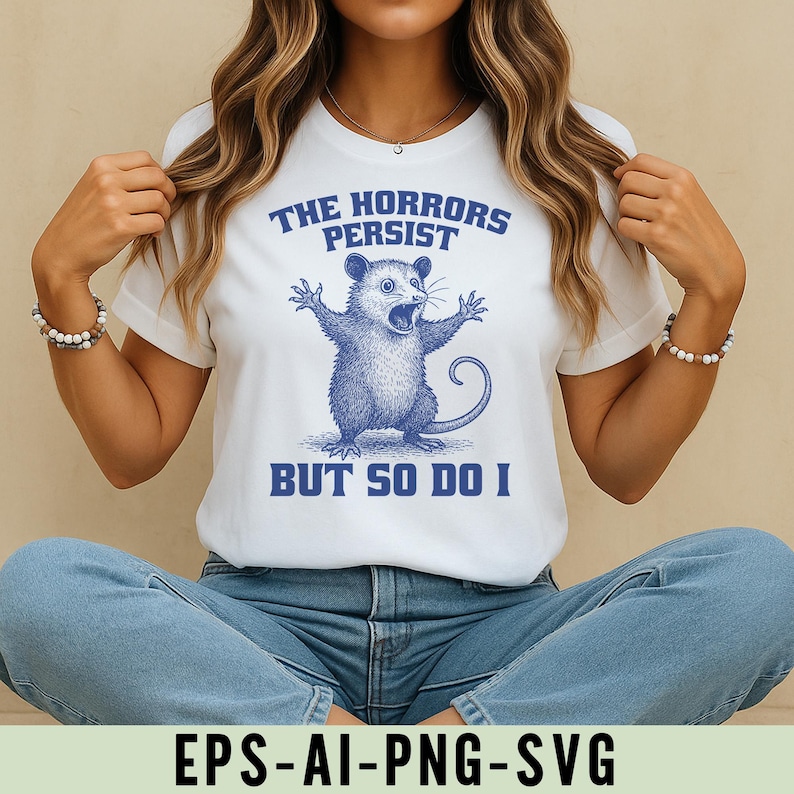 May include: White t-shirt with a blue opossum graphic and the words "THE HORRORS PERSIST BUT SO DO I". The design features a detailed illustration of an opossum. The t-shirt is made of a soft material.