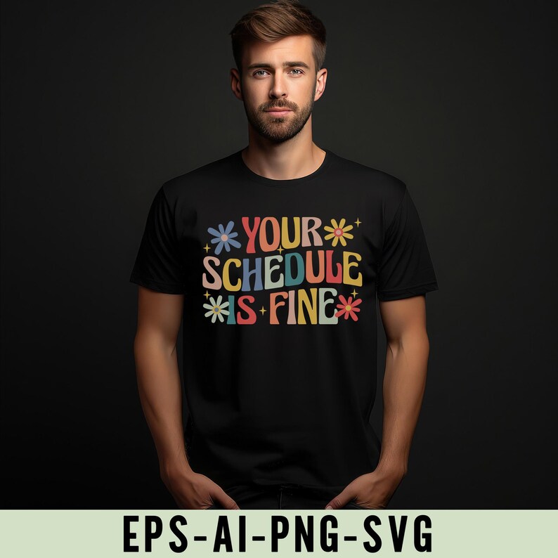 Pu&ograve; includere: T-shirt nero con la scritta "YOUR SCHEDULE IS FINE" in lettere colorate in stile retr&ograve;. Il design include accenti floreali. La maglietta &egrave; girocollo e viene indossata da una persona.