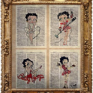 May include: A framed artwork with four panels of Betty Boop illustrations on vintage dictionary pages, set within an ornate gold frame. Each panel shows Betty Boop in various poses, rendered in a classic cartoon style.