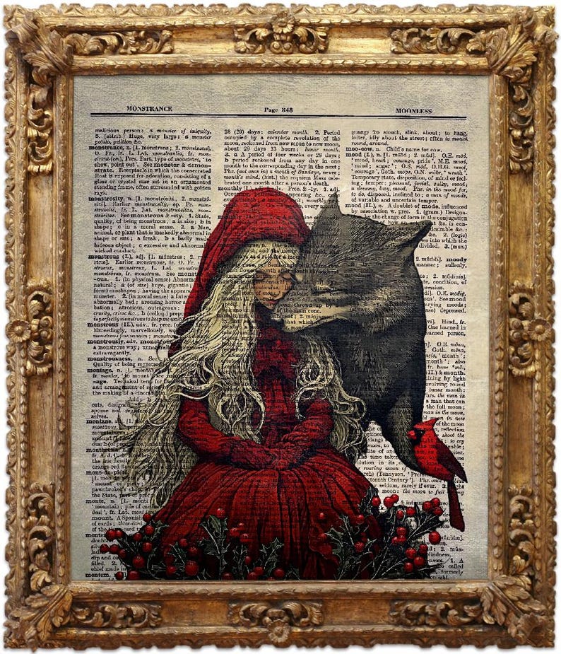 Puede incluir: Una impresi&oacute;n enmarcada con una ilustraci&oacute;n vintage de Caperucita Roja y el lobo, sobre un fondo de p&aacute;ginas de diccionario antiguas. La obra de arte est&aacute; en un marco dorado ornamentado. Un p&aacute;jaro cardenal rojo est&aacute; posado en la ilustraci&oacute;n.