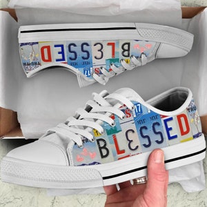 May include: White canvas low-top sneakers with a colorful design featuring the word "BLESSED" spelled out using license plates.