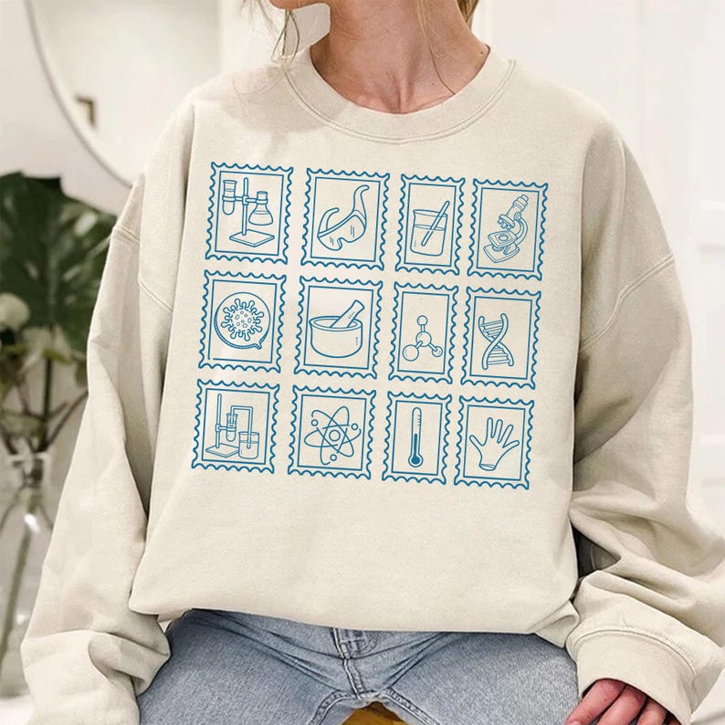 Pu&ograve; includere: Felpa beige con una griglia di disegni di francobolli blu a tema scientifico. Ogni francobollo mostra una diversa illustrazione scientifica, tra cui becher, microscopi e strutture molecolari. La felpa &egrave; realizzata in materiale morbido.