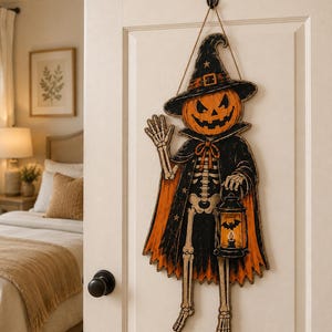 May include: A hanging wall decoration featuring a skeleton figure with a jack-o'-lantern head, wearing a black and orange witch hat and cape. The figure holds a black lantern with a bat silhouette and waves with one hand, suspended by a twine cord.