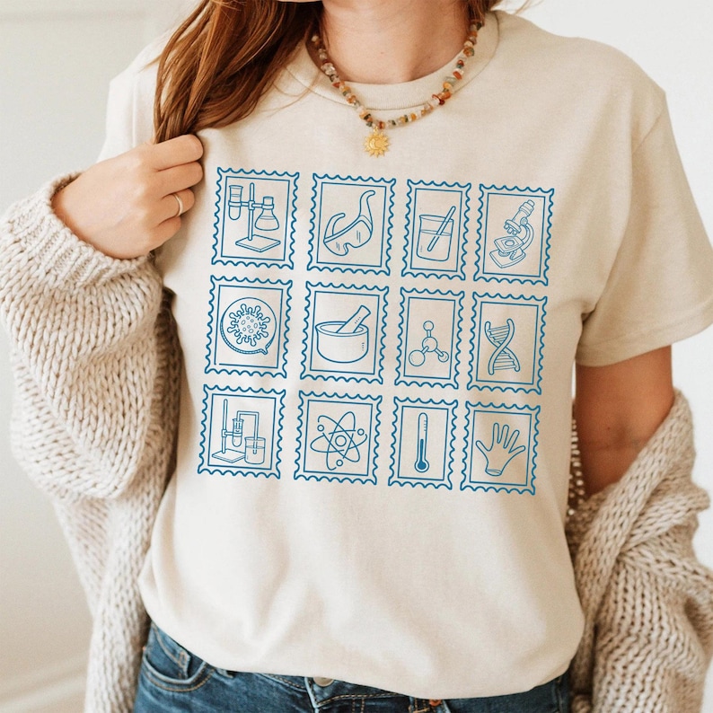 Pu&ograve; includere: T-shirt beige con una griglia di francobolli blu a tema scientifico. I francobolli raffigurano attrezzature da laboratorio, molecole e simboli scientifici. La maglietta &egrave; realizzata in materiale morbido e ha uno scollo tondo.