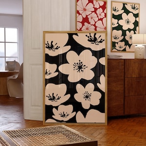 May include: Three framed floral prints with black and white, red and white, and green and white floral patterns. The prints are hanging on a white wall above a wooden dresser.