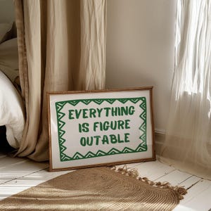 Pu&ograve; includere: Una stampa incorniciata con la scritta "EVERYTHING IS FIGURE OUTABLE" in verde. La stampa ha un bordo verde decorativo ed &egrave; ambientata su uno sfondo bianco. La cornice &egrave; di colore marrone chiaro. Un tappeto tessuto &egrave; in primo piano.