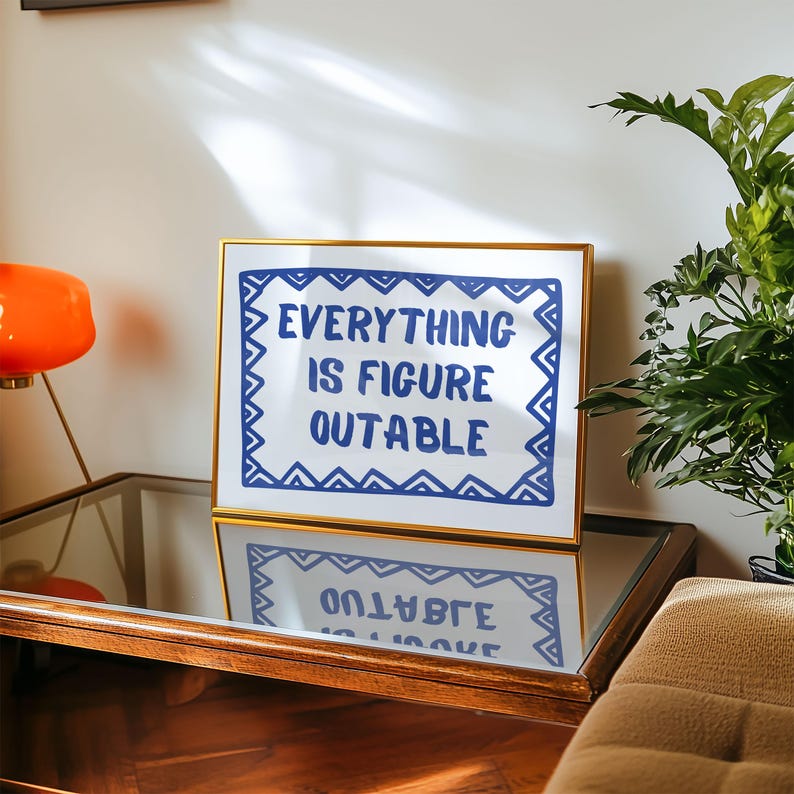 May include: A gold framed print with a white background and blue text that reads "EVERYTHING IS FIGURE OUTABLE" surrounded by a blue and white geometric border.