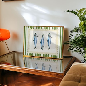 May include: A framed print with a green and white striped border. The print features three blue fish on a white background.