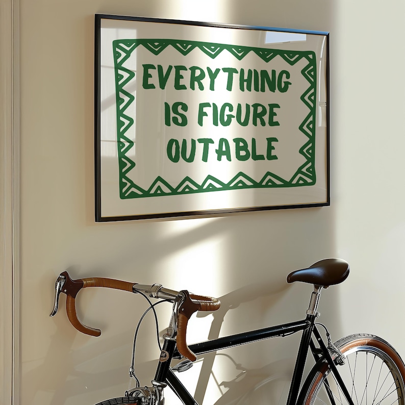 Pu&ograve; includere: Una stampa incorniciata con la scritta "EVERYTHING IS FIGURE OUTABLE" in verde. Sotto, una bicicletta nera con manubrio marrone e sella marrone. La bicicletta &egrave; montata su un muro bianco.