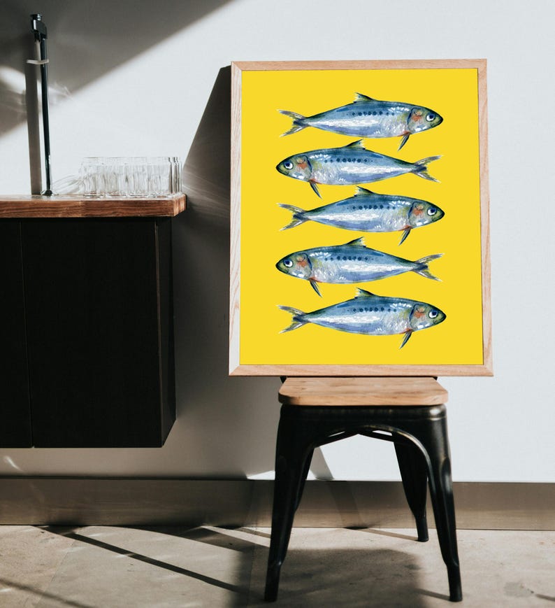May include: A framed print of five blue and silver fish on a yellow background. The fish are arranged in a vertical line, with their tails facing the bottom of the frame.