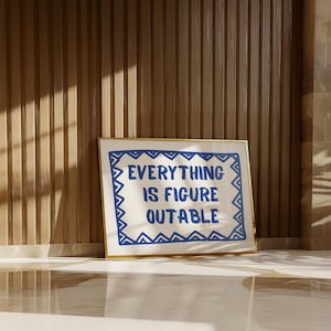 May include: A framed print with a white background and a blue border. The text "EVERYTHING IS FIGURE OUTABLE" is written in blue letters inside the border.