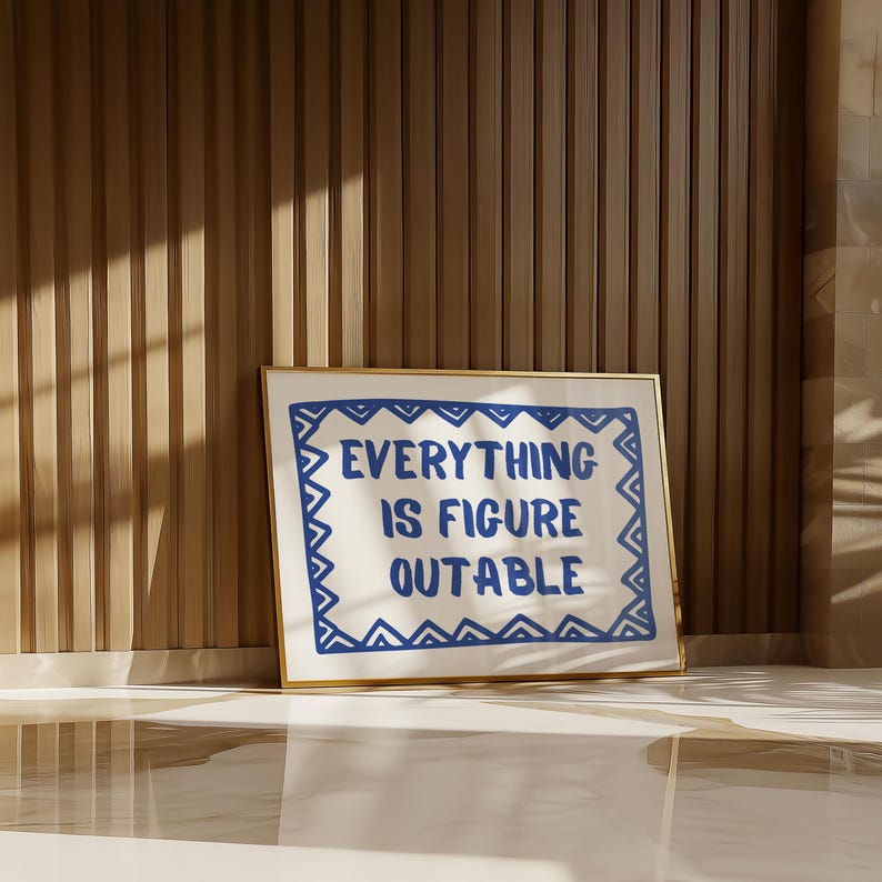 May include: A framed print with a white background and a blue border. The text "EVERYTHING IS FIGURE OUTABLE" is written in blue letters inside the border.