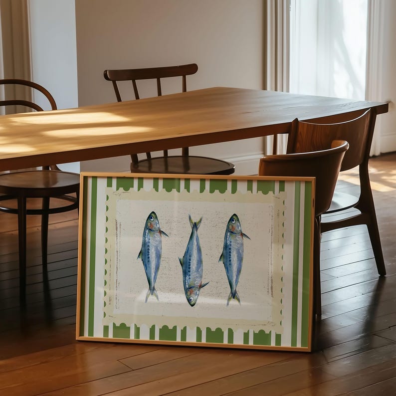 May include: A framed print of three blue fish on a white background with a green and white striped border. The fish are arranged in a row, with their tails facing each other.