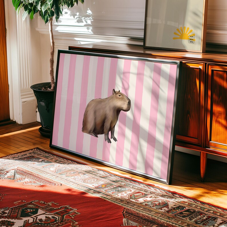 Op de afbeelding: Een bruine capibara staat op een roze en witte gestreepte achtergrond. De capibara kijkt naar de rechterkant van de afbeelding.