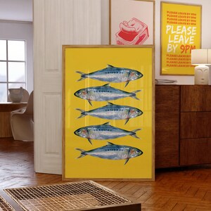 May include: A framed print with a yellow background and five blue and silver fish. The text "PLEASE LEAVE BY 9PM" is repeated multiple times in red and yellow on a white background in a separate frame.