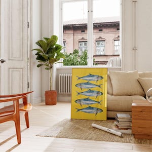 May include: A framed print of five blue fish on a yellow background. The fish are arranged in a row, with their tails facing the right side of the image.