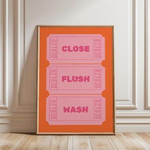 May include: A pink and orange bathroom sign with three ticket-shaped panels. The panels have the words "CLOSE", "FLUSH", and "WASH" printed on them.
