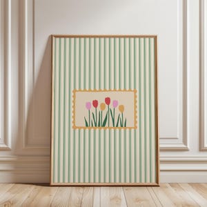 Puede incluir: Una impresión artística enmarcada con un diseño floral. La obra de arte muestra una imagen rectangular en forma de sello con tulipanes coloridos sobre un fondo crema. El marco es de color marrón claro, y el fondo tiene rayas verticales verdes y crema.
