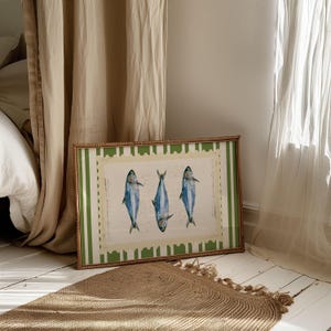 May include: A framed print with a green and white striped border. The print features three blue fish with white bellies, arranged in a row.