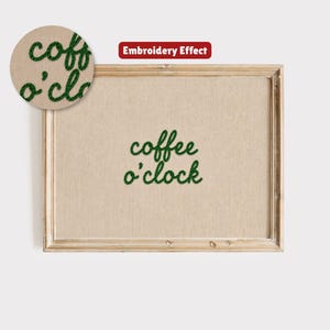Op de afbeelding: Een ingelijst kunstwerk met de zin "coffee o'clock" geborduurd in groen garen. Het kunstwerk heeft een lichtbruine achtergrond en een houten lijst. Een close-up toont het borduureffect.