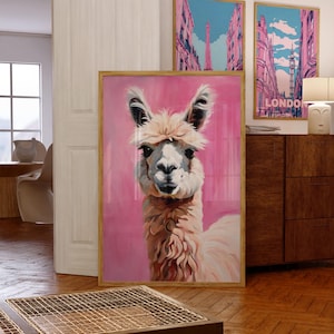 May include: A framed painting of a fluffy white llama with brown fur on its neck and head, looking directly at the viewer. The background is a solid pink color.