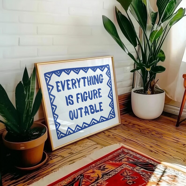 May include: A gold framed print with a white background and blue text that reads "EVERYTHING IS FIGURE OUTABLE" surrounded by a blue and white geometric pattern.