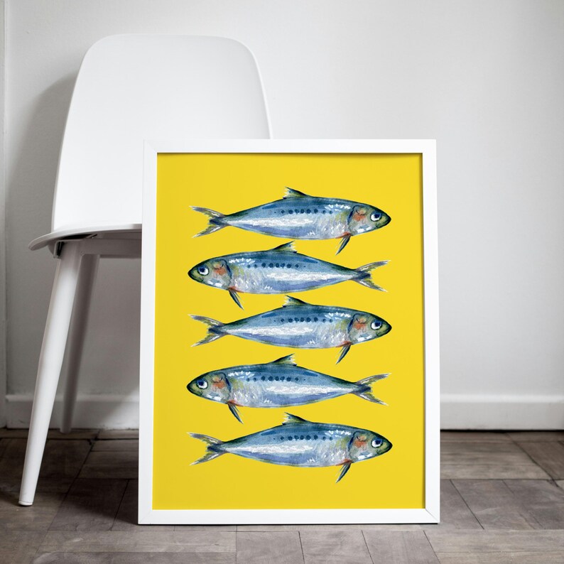 May include: A framed print with a yellow background featuring five blue and silver fish arranged in a vertical row. The fish are all facing the right side of the image.