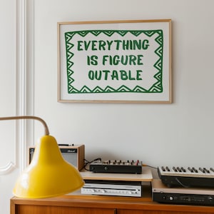 Pu&ograve; includere: Una stampa incorniciata con la scritta "EVERYTHING IS FIGURE OUTABLE" in verde su sfondo bianco. La stampa &egrave; appesa sopra un mobile in legno con una lampada gialla, un piccolo amplificatore e apparecchiature musicali elettroniche.