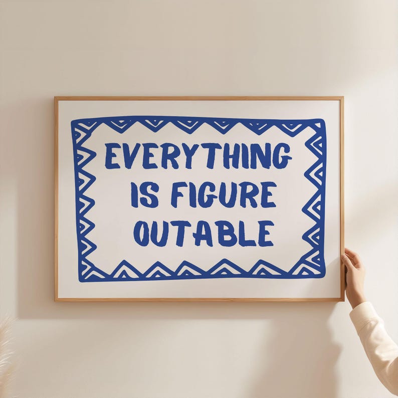May include: A framed print with a white background and a blue border. The print features the text "EVERYTHING IS FIGURE OUTABLE" in blue.