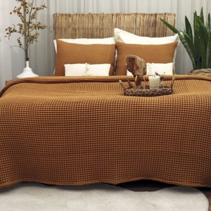 on the double bed with decorations on the back and on it. there is a custom size waffle bedspread made of organic cotton. the caramel coloured waffle cover can also be used as a TV blanket