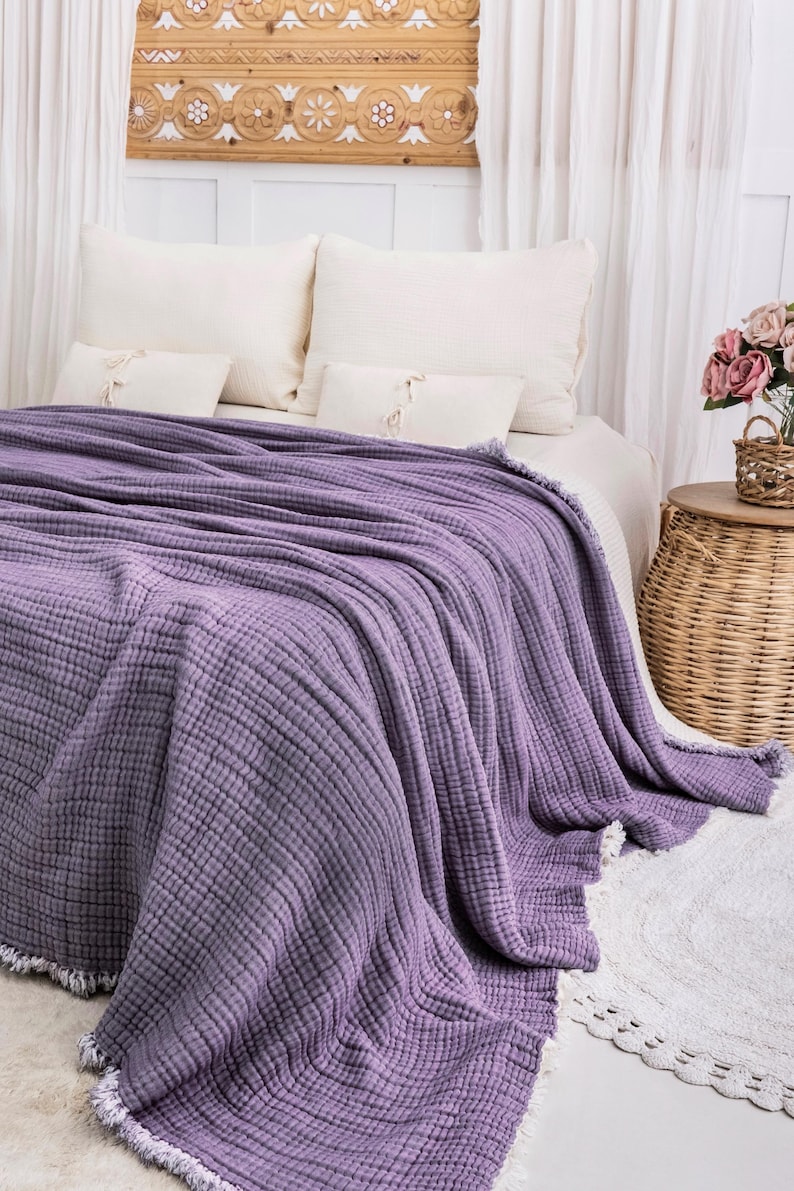K&ouml;nnte beinhalten: Eine weiche, violette Waffel-Decke mit Fransenrand. Die Decke liegt auf einem Bett mit wei&szlig;en Kissen und einer wei&szlig;en Bettdecke.