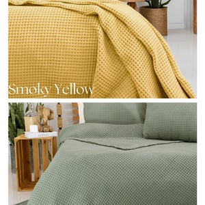 May include: Two waffle-weave bedspreads in smoky yellow and sage green. The yellow bedding is draped over a bed with matching pillows. The sage green bedding is neatly arranged with pillows and a folded blanket. The text "Smoky Yellow" and "Sage Green" are visible.