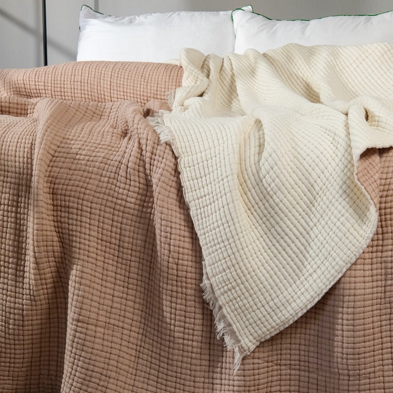 K&ouml;nnte beinhalten: Zwei Waffel-Decken, eine in hellem Beige und eine in staubigem Rosa, liegen &uuml;ber einem Bett mit wei&szlig;en Kissen.