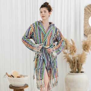 May include: A colorful, hooded bathrobe with a textured dot pattern. The robe features a tie waist and fringe detailing at the hem and sleeves. The color palette includes a variety of bright hues, including blue, green, red, and yellow.