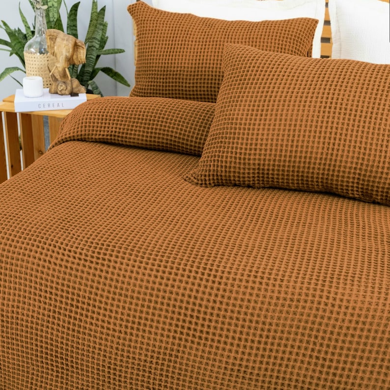 May include: A bed set with a waffle weave pattern in a warm, earthy brown color. The set includes a duvet cover and two pillowcases. The bedding is neatly arranged, suggesting a comfortable and inviting bedroom setting.
