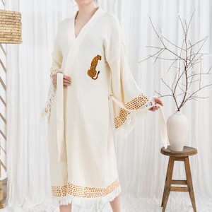 Pode incluir: Robe creme com uma aplica&ccedil;&atilde;o de leopardo. O robe apresenta um design envolvente, mangas compridas com um padr&atilde;o de pontos e acabamento com franjas. Um cinto a condizer &eacute; amarrado na cintura. O robe &eacute; feito de um tecido texturizado.