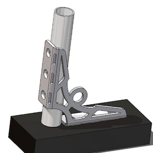 May include: A silver metal bracket with a decorative design, attached to a cylindrical tube. The bracket is mounted on a black rectangular base. The design includes multiple holes and a curved, openwork pattern.