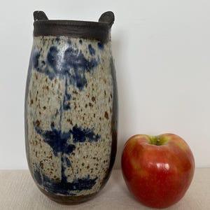 Puede incluir: Un jarrón de cerámica marrón y azul con un esmalte moteado y un diseño único. El jarrón tiene dos pequeñas asas en la parte superior y es aproximadamente del tamaño de una manzana.