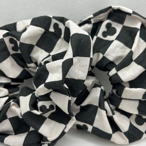 May include: Two black and white checkered hair scrunchies with a small Mickey Mouse silhouette pattern.