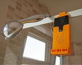 May include: Orange phone holder with a logo and a row of holes for drainage, attached to a shower door with a black phone inside.