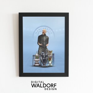 May include: A framed print of a man in a black jacket standing in front of three trophies. The trophies are silver and gold and have a blue and white design. The background is a light blue color with the words "Manchester" in a circle.
