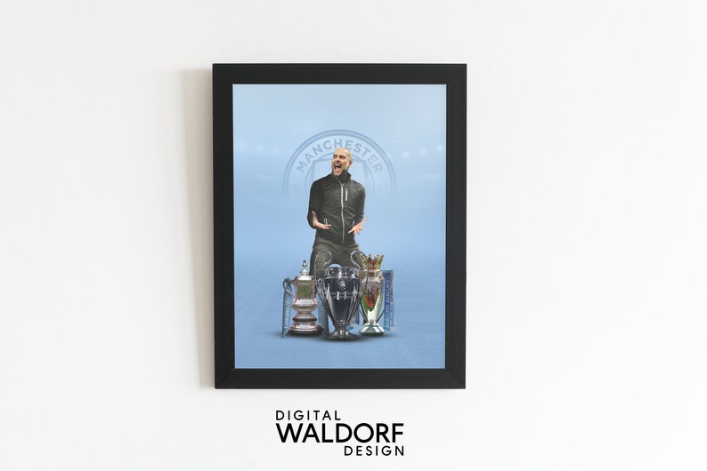 May include: A framed print of a man in a black jacket standing in front of three trophies. The trophies are silver and gold and have a blue and white design. The background is a light blue color with the words "Manchester" in a circle.