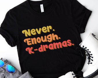 Puede incluir: Camiseta negra con el texto "Never. Enough. K-dramas." en una fuente retro con colores amarillo, naranja y rojo.
