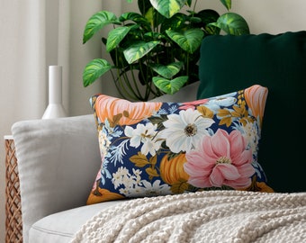 May include: A decorative throw pillow with a floral pattern featuring pumpkins, flowers, and leaves on a dark blue background.