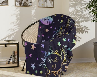 May include: A soft, plush throw blanket with a celestial design. The blanket features a rainbow-coloured sun and moon with stars on a dark blue background.