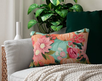 May include: A decorative throw pillow with a floral and pumpkin design. The pillow features pink, orange, and green colors on a light blue background.