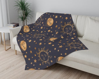 May include: A navy blue throw blanket with a gold celestial pattern featuring suns, moons, and stars.
