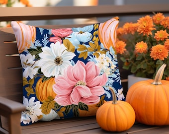 May include: A blue and white floral throw pillow with pumpkins and leaves. The pillow is sitting on a wooden bench with two pumpkins in front of it.