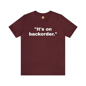 Könnte beinhalten: Ein maroonfarbenes T-Shirt mit weißem Text, der "It's on backorder." lautet.